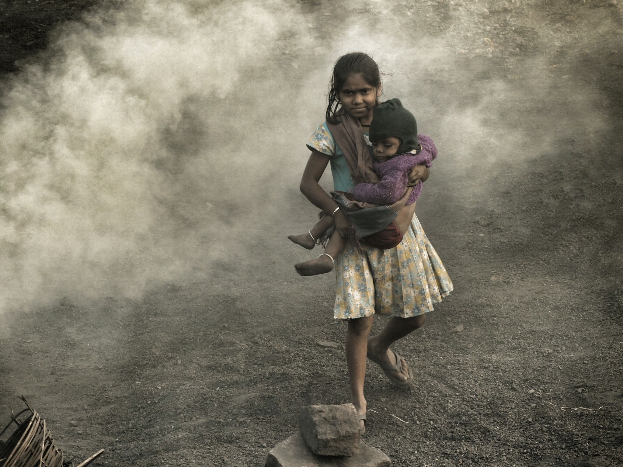 A girl carries her sister though burning coal fires at Ganshadih.