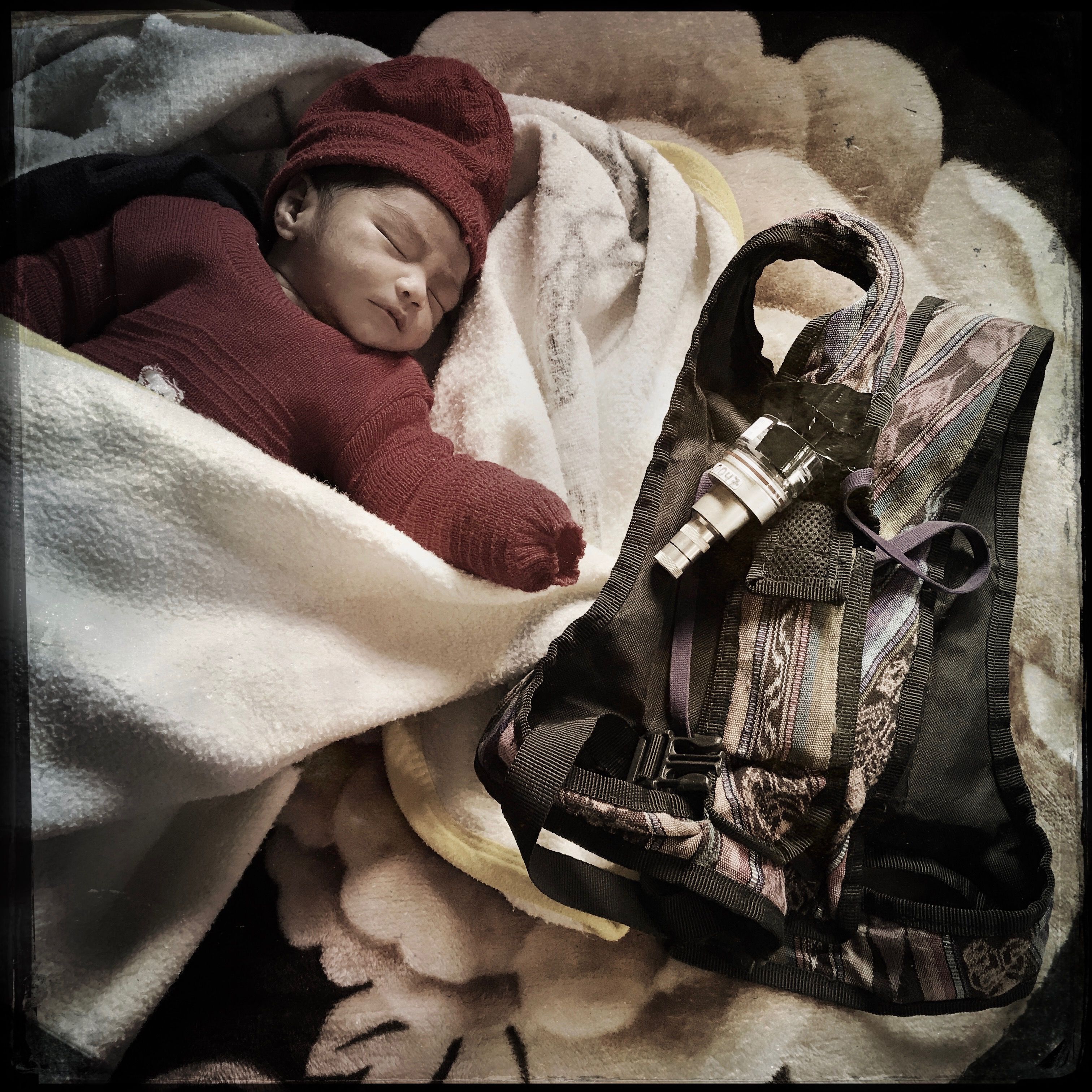 In the highlands of Guatemala, Dina Marroquín’s eight-day-old baby rests next to a knapsack holding an indoor air monitor—part of study to determine whether the use of gas stoves improves household air quality and children’s health. Photo by Lynn Johnson. Guatemala, 2017.