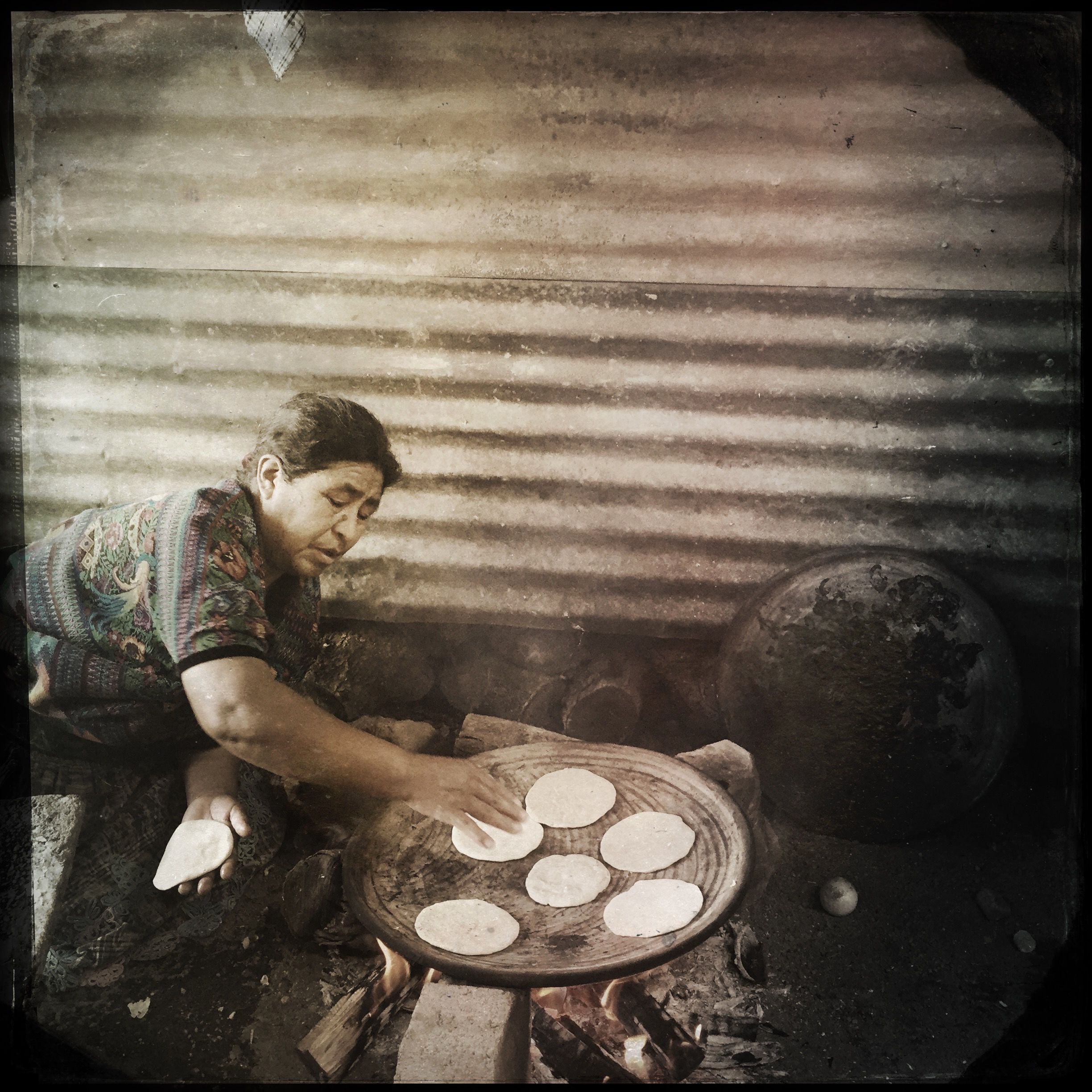 Maria de Jesus Lopez Pérez, 62, spends some three hours a day on her knees over an open fire, making tortillas for her extended family in San Antonio Aguas Calientes, Guatemala. Photo by Lynn Johnson. Guatemala, 2017.