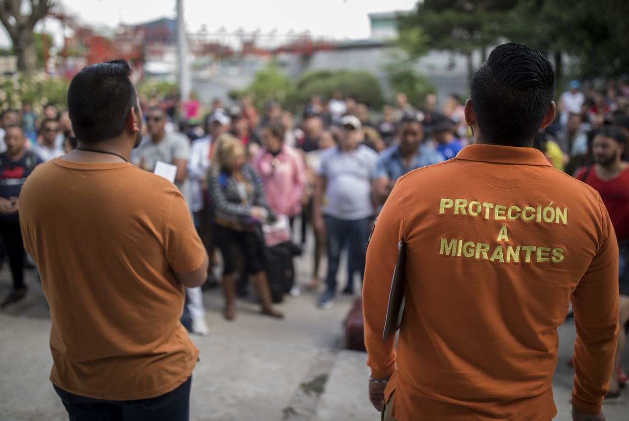 Workers from the Centro de Atención Integral a Migrantes (CAIM) call out numbers from the asylum waiting list outside the center in Ciudad Juárez on May 13, 2019. Image by Ivan Pierre Aguirre. Mexico, 2019.