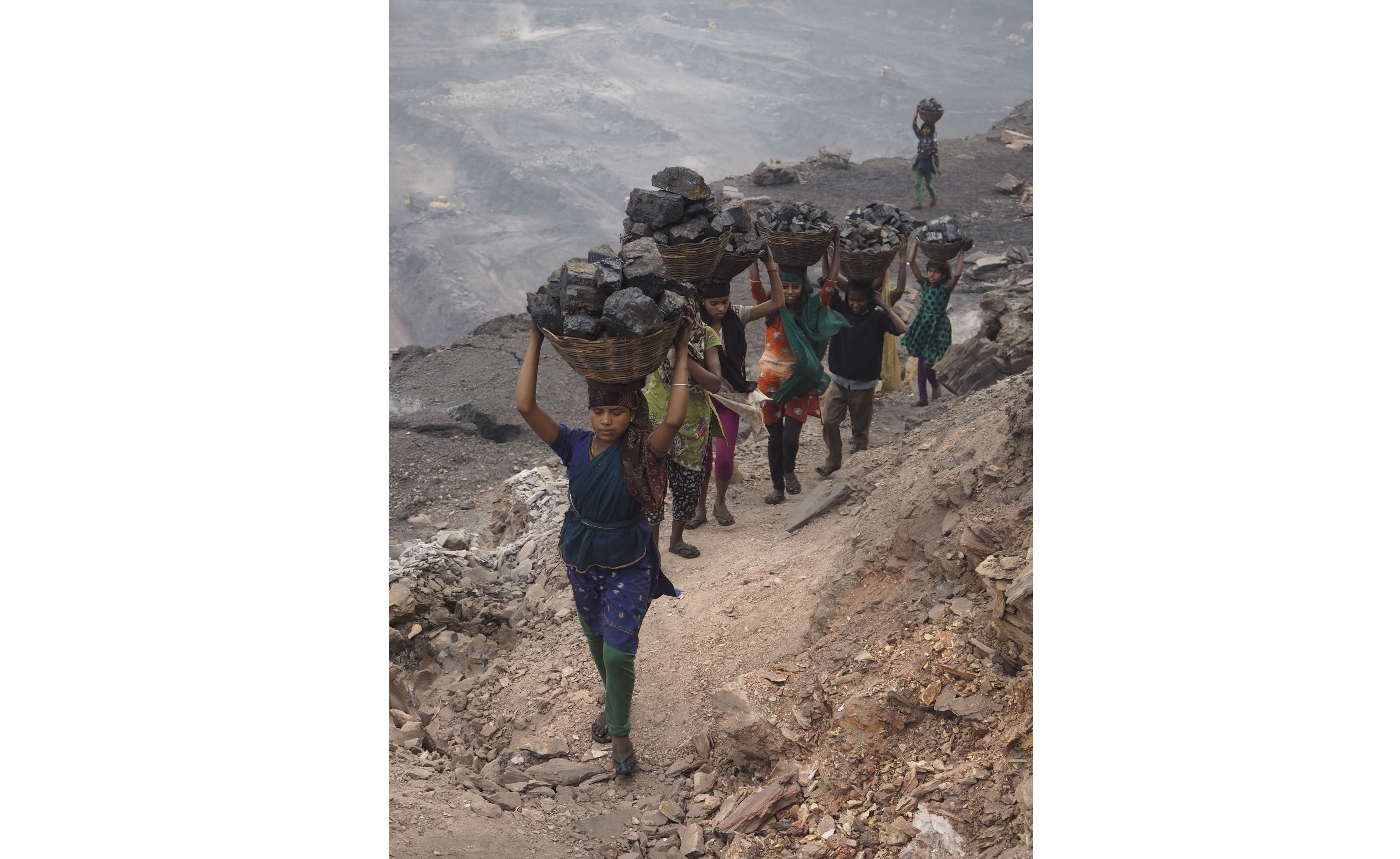 Women and young girls carry scavenged coal from the bottom of the Alkusha Coalfield. Image by Larry C. Price. India, 2016.
