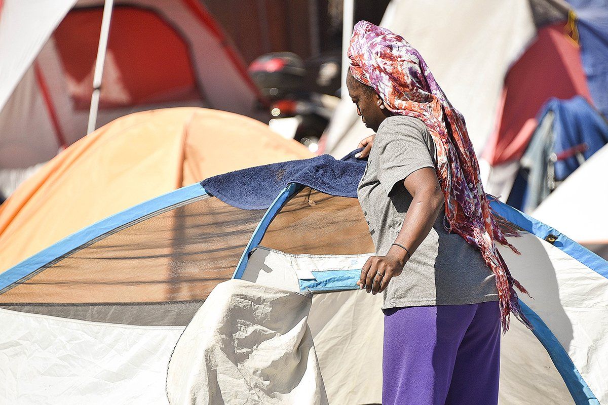 A woman in the Lots, a homeless encampment in Phoenix, drapes a towel over her tent on June 24, when the high in Phoenix hit 111 degrees. Donated tents are available for homeless people who don’t have their own. Image by Steve Carr/Human Services Campus. United States, 2020.