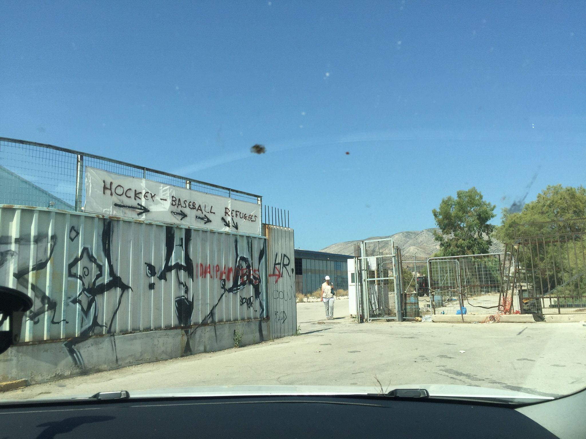 The official entrance to the Elliniko refugee camp in Athens, in which thousands of displaced people are warehoused in an abandoned hockey stadium and baseball stadium, built for the 2004 Olympics, and a former airport arrivals building. Image by Sonia Shah. Greece, 2016.