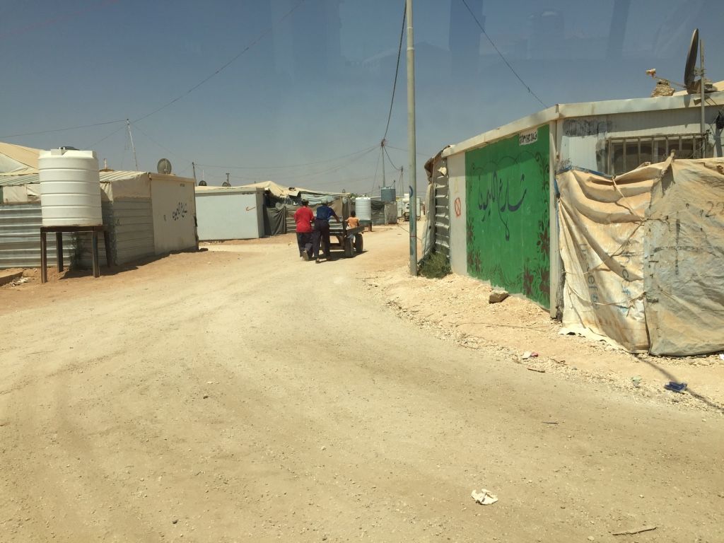 Men push a cart down the dusty roads of Za'atari. Image by Rachel Townzen. Jordan, 2016.