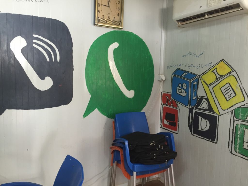 Social media icons for Viber and WhatsApp, two of the most preferred apps for refugees, appear on the walls of small computer caravans in Azraq Camp, such as this one. Image by Rachel Townzen. Jordan, 2016.