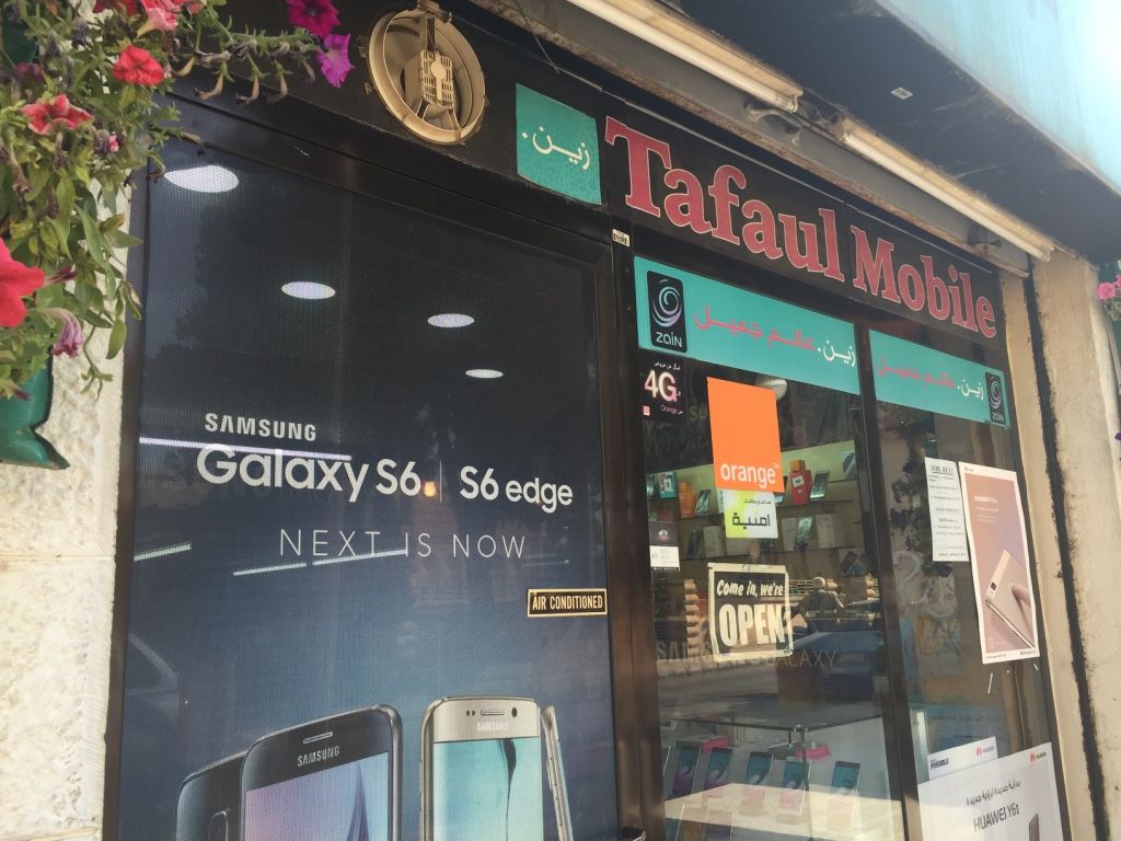 A cell-phone store in Amman advertising Orange and Zain, two of three network carriers in Jordan. When new refugees register with UNHCR, the UN Refugee Agency, they receive a Jordanian SIM card so that UNHCR can send updates and communicate with a massive and dispersed refugee community. Image by Rachel Townzen. Jordan, 2016.