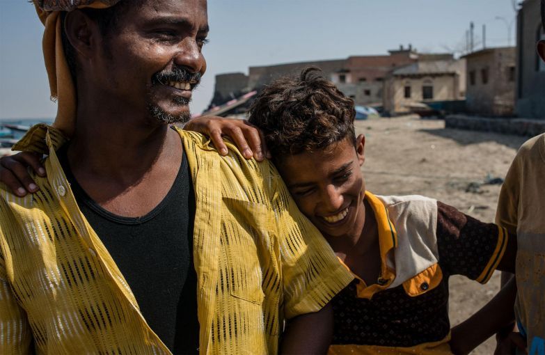 Shafai Saleh Hadi (left) laughs with local boys on the shore of Bir Fuqum. As a first-generation fisherman, he sees the job as a better route for his sons than attending school, since employment is incredibly scarce in Yemen. Image by Alex Potter. Yemen, 2018.
