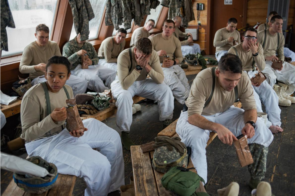 U.S. soldiers eat high-calorie rations to help their bodies deal with the cold at the Northern Warfare Training Center in Alaska, where the Army conducts cold-region training. The soldiers learn tactics derived from the Winter War, fought between Finland and the Soviet Union in World War II. Image by Louie Palu. United States, 2019.