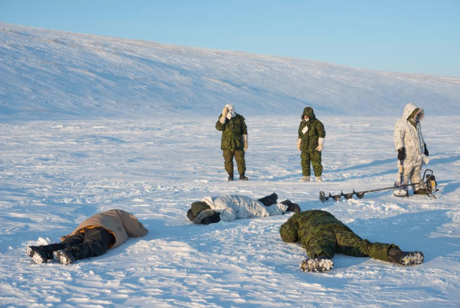 After using a gas-powered auger to drill holes in the ice at the north end of Cornwallis Island, Canadian rangers set nets to fish for arctic char. Image by Louie Palu. Canada, 2019.
