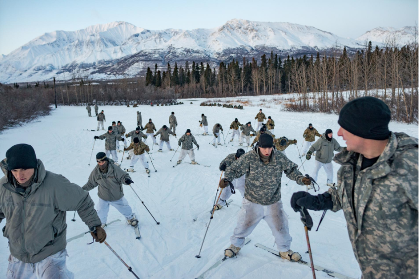 U.S. soldiers practice climbing a hill while wearing skis at Alaska’s Northern Warfare Training Center, where troops learn a range of skills—from dressing for the extreme cold and basic snowshoeing to skiing with a rifle and towing a 200-pound sled. Image by Louie Palu. United States, 2019.
