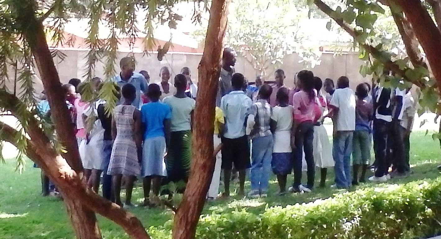 A group session under the tree at Tiwale Teen Club in Lilongwe.