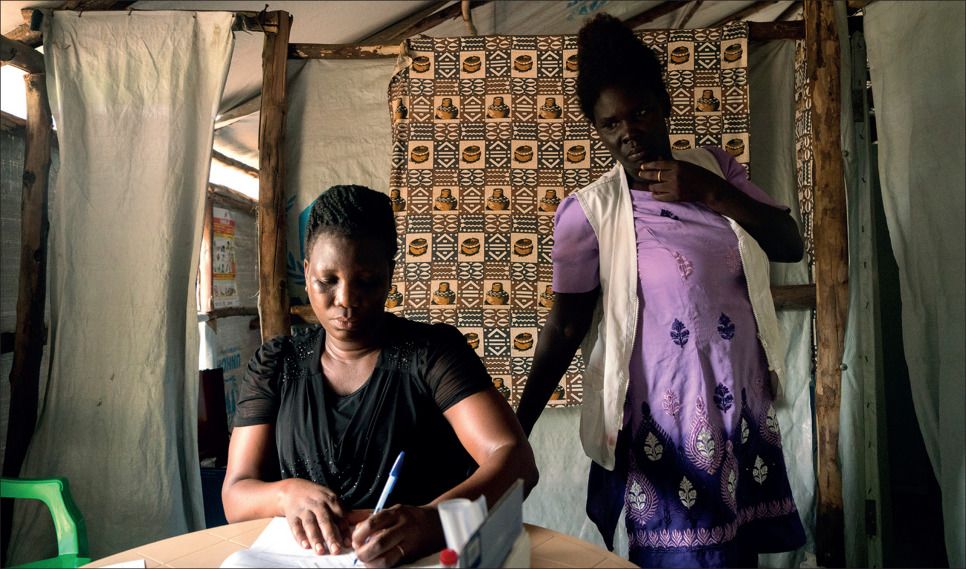 Midwife Susan Oyera, with the help of medical interpreter Grace Ezati, writes a referral for a patient who has a positive HIV test to speak with a psychologist at the Médecins Sans Frontières sexual violence and mental health clinic in the Omugo settlement in the Rhino camp extension in Uganda for refugees from South Sudan.