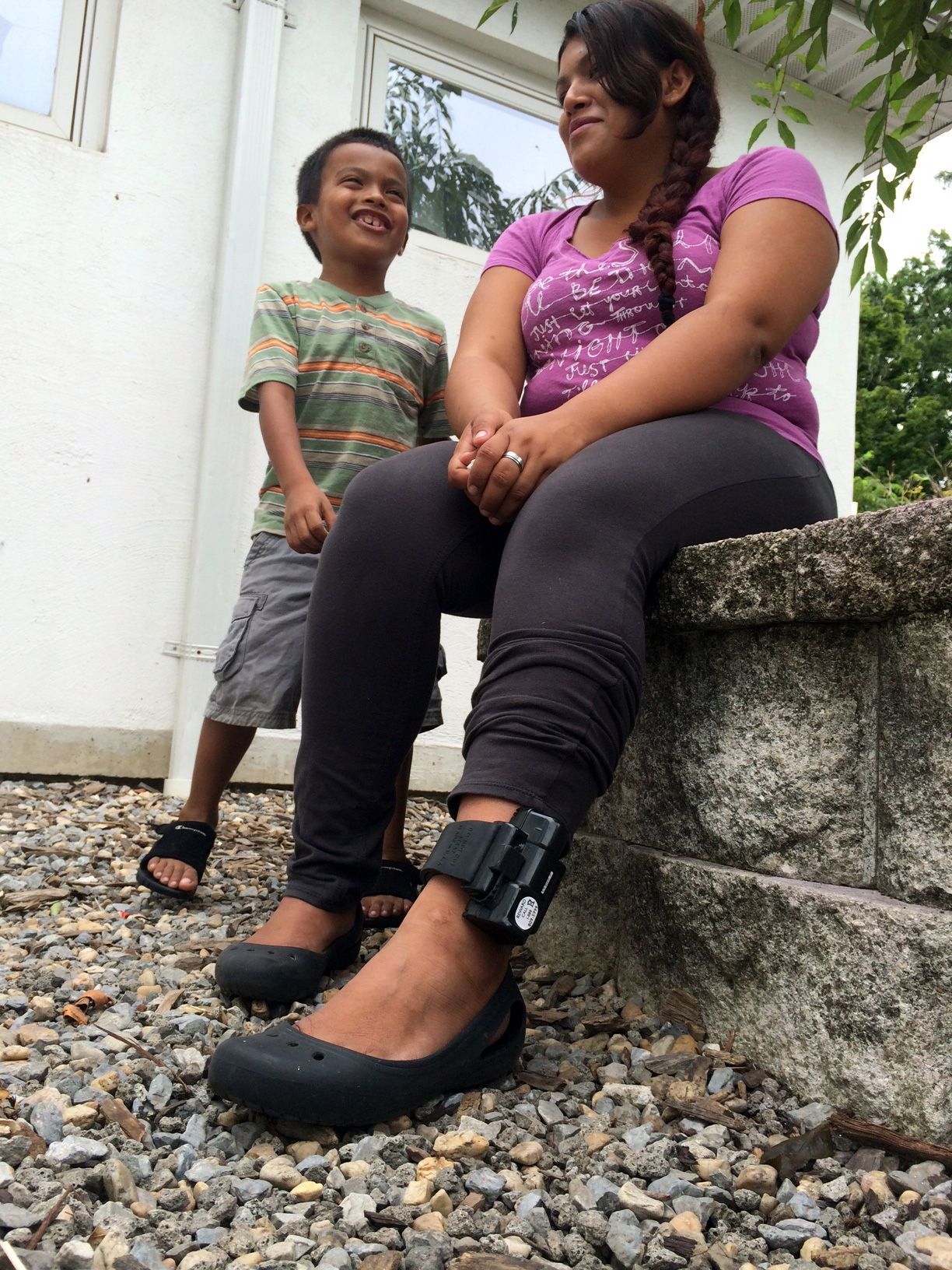 A mother, who is wearing an ankle monitor, sits with her son.