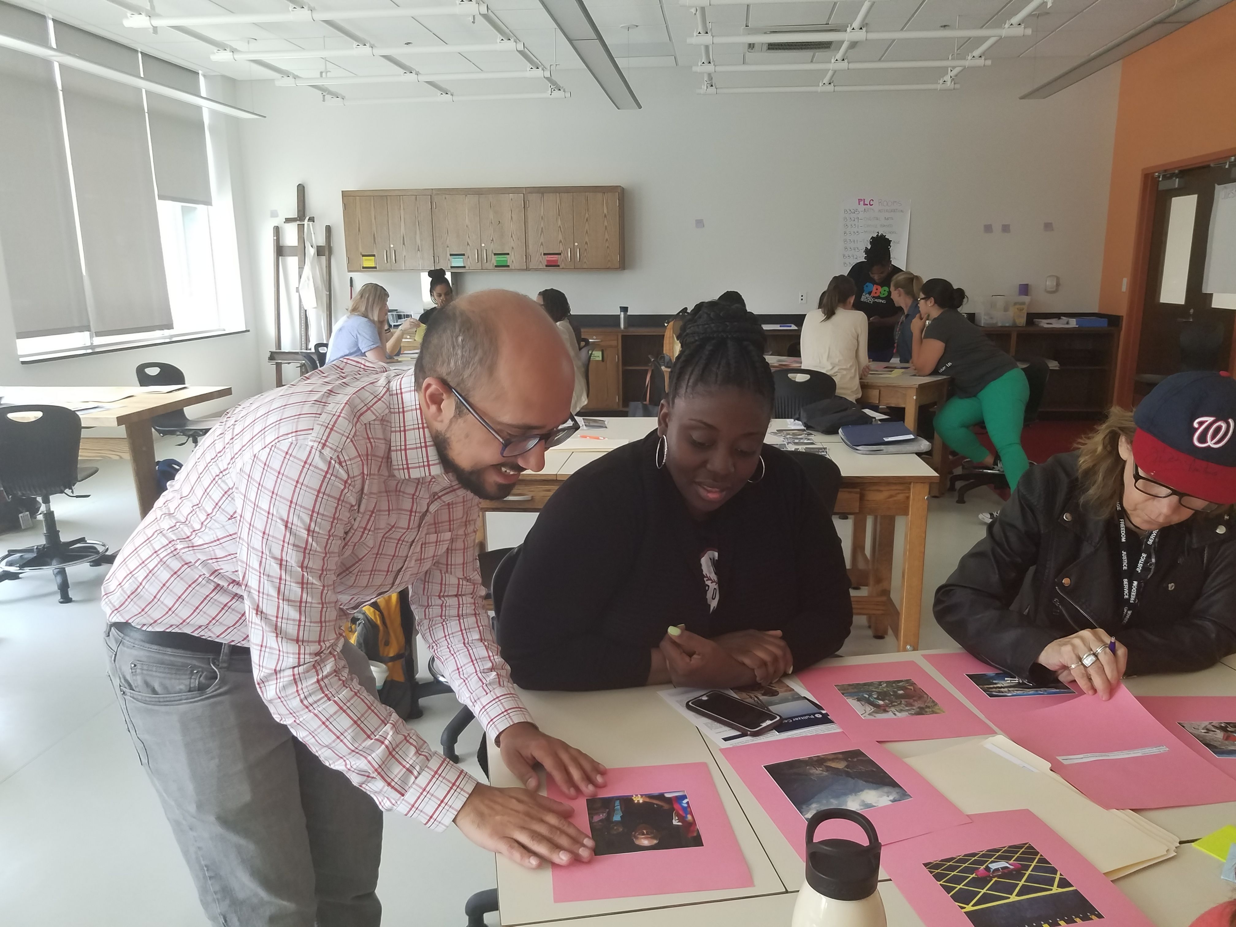 Teachers look at photos from the Everyday series as Fareed Mostoufi from the Pulitzer Center guides them through the Everyday DC unit. Image by Kayla Sharpe. United States, 2017.
