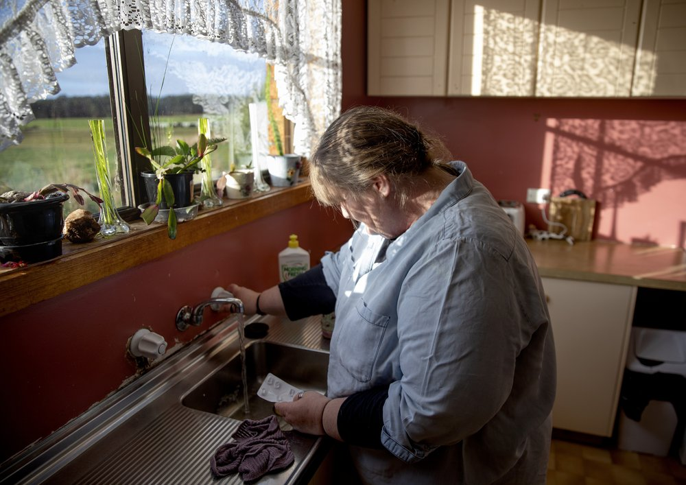 Carmall Casey washes pills from an old pack of tapentadol down the sink while going through her box of medicine in her kitchen in Black River, Tasmania, Australia, Wednesday, July 24, 2019. She thought she had thrown all her opioids away. Casey's tried to quit in the past, returning drugs to pharmacies and dumping them down the sink. But eventually, the pain would grow unbearable, so she'd take the drugs again. Image by David Goldman. Australia, 2019.