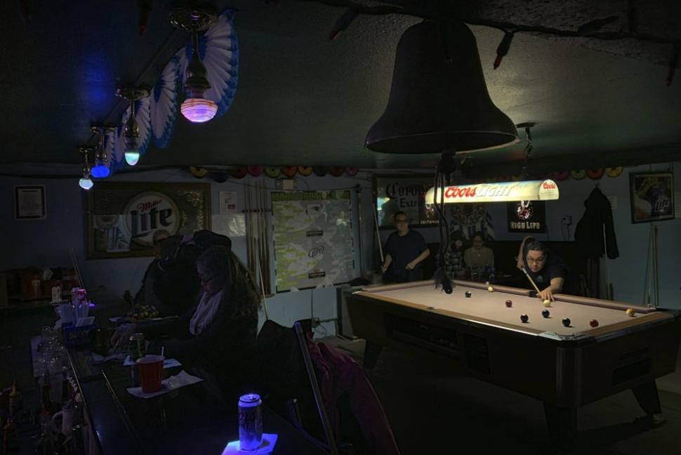 In this Feb. 23, 2019, photo, people play pool while some sit at the bar with their drinks at Soap and Suds, a popular nighttime spot, on Front Street in Nome, Alaska. Image by Wong Maye-E. United States, 2019.
