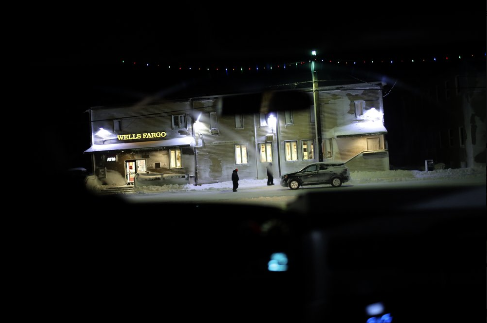 In this Feb. 13, 2019 photo, people walk past a commercial bank in the morning darkness on Front Street in Nome, Alaska. Image by Wong Maye-E. United States, 2019.