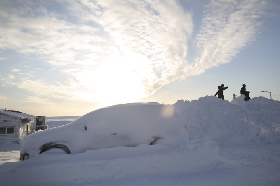 In this Feb. 14, 2019, photo, children play on a snow berm near the shores of the Bearing Sea in Nome, Alaska. Nome is approximately 100 miles from Siberia and serves as the commercial hub for Alaska's Bearing Strait region. Image by Wong Maye-E. United States, 2019.