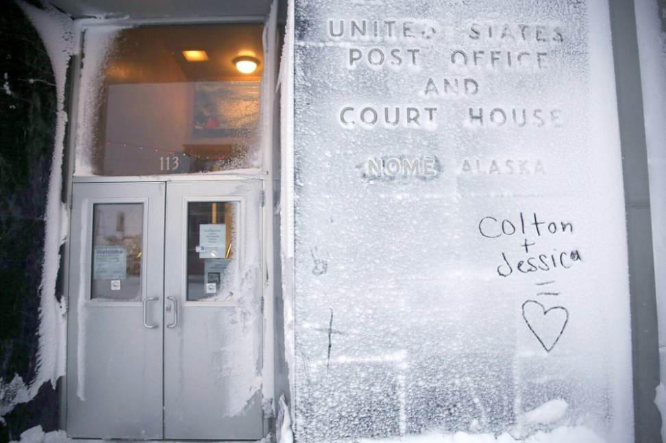 In this Feb. 13, 2019, photo, the names of two lovers are etched onto a snow-covered wall of the United States Post Office and Court House in Nome, Alaska. Image by Wong Maye-E. United States, 2019.