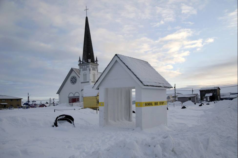 In this Feb. 14, 2019, photo, a school bus stop stands in front of Old St. Joe's Hall, built in 1901 by a Jesuit priest in Nome, Alaska. Image by Wong Maye-E. United States, 2019.