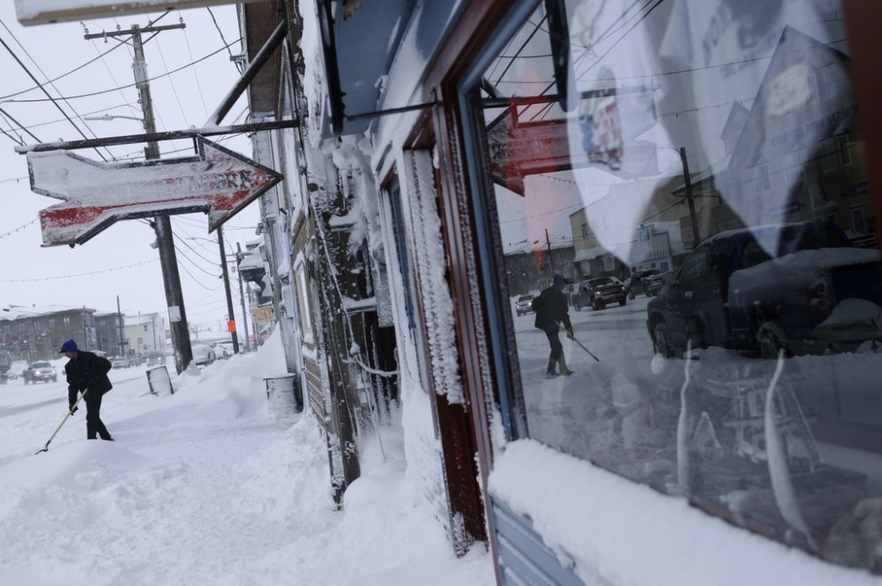 In this Feb. 22, 2019, photo, a man shovels snow outside the Polar Bar and Cafe on Front Street in Nome, Alaska. Image by Wong Maye-E. United States, 2019.