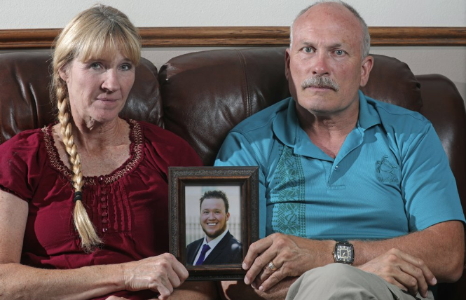 In this Monday, Sept. 9, 2019, photo, Rod and Tonya Meldrum hold a portrait of their son Devin Meldrum, in Provo, Utah. He suffered from debilitating cluster headaches and fatally overdosed after taking a single fentanyl-laced counterfeit oxycodone pill purchased from a dark-web store run by Aaron Shamo, according to his family and authorities. Shamo was not charged in Meldrum’s death, and his lawyers have argued that and other alleged overdoses can’t be definitively linked to him. Image by Rick Bowmer. United States, 2019.