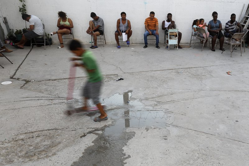 In this July 26, 2019, photo, people from Africa and Central America sit in chairs as the sun sets at El Buen Pastor shelter for migrants in Cuidad Juarez. Image by Gregory Bull. Mexico, 2019. 