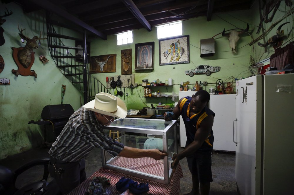In this July 30, 2019, photo, Desidero Ojeda, left, of Texas, works with Alphat, of Uganda in repairing a display case at Ojeda's corner store near El Buen Pastor shelter for migrants, where Alphat is staying, in Cuidad Juarez, Mexico. Image by Gregory Bull. Mexico, 2019.