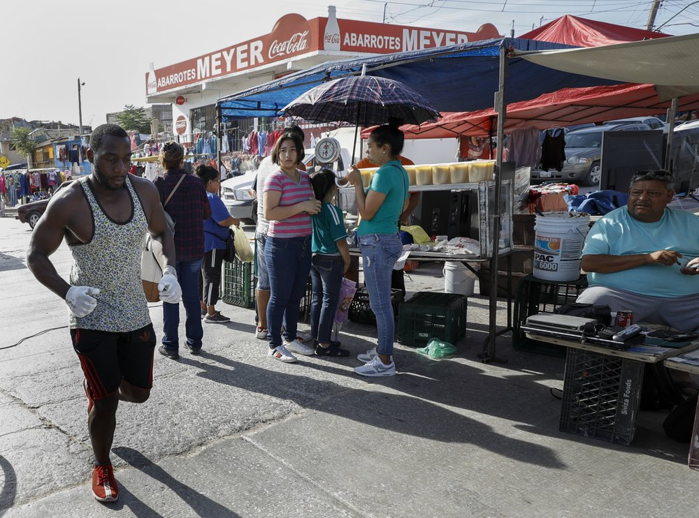 In this July 31, 2019, photo, Alphat, of Uganda runs through a neighborhood surrounding the El Buen Pastor shelter for migrants in Cuidad Juarez, Mexico. Alphat runs relentlessly, and seemingly effortlessly. People stop to stare, surprised to see a black man with ham-sized biceps and impossibly broad shoulders running through this city, which has long been a magnet for migrants. Image by Gregory Bull. Mexico, 2019.