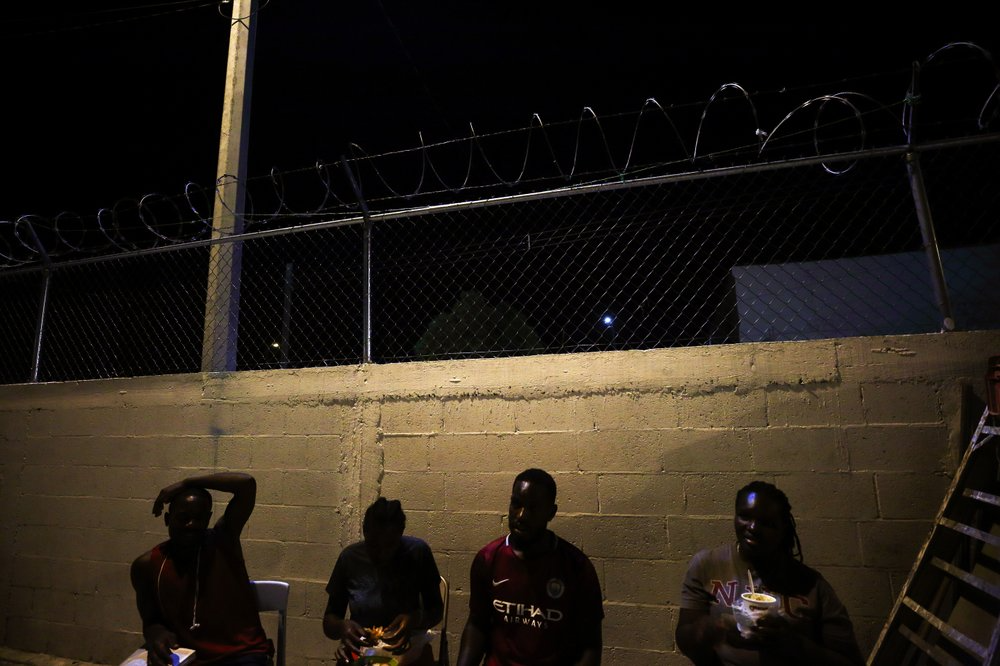 In this July 24, 2019, photo, Africans sit in folding chairs at Buen Pastor migrant shelter in Cuidad Juarez, Mexico. They are part of the cobbled-together community of El Buen Pastor - The Good Pastor - 134 migrants from around the world locked into a shelter every evening at 5:30 p.m., trapped in an immigration purgatory barely three miles from the Paso del Norte Bridge and an easy walk to their goal: The United States. Image by Gregory Bull. Mexico, 2019. 