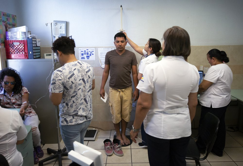 In this July 25, 2019, photo, Samuel, of Honduras, center, is treated at a clinic after taking a bus from El Buen Pastor shelter for migrants in Cuidad Juarez, Mexico. Image by Gregory Bull. Mexico, 2019. 