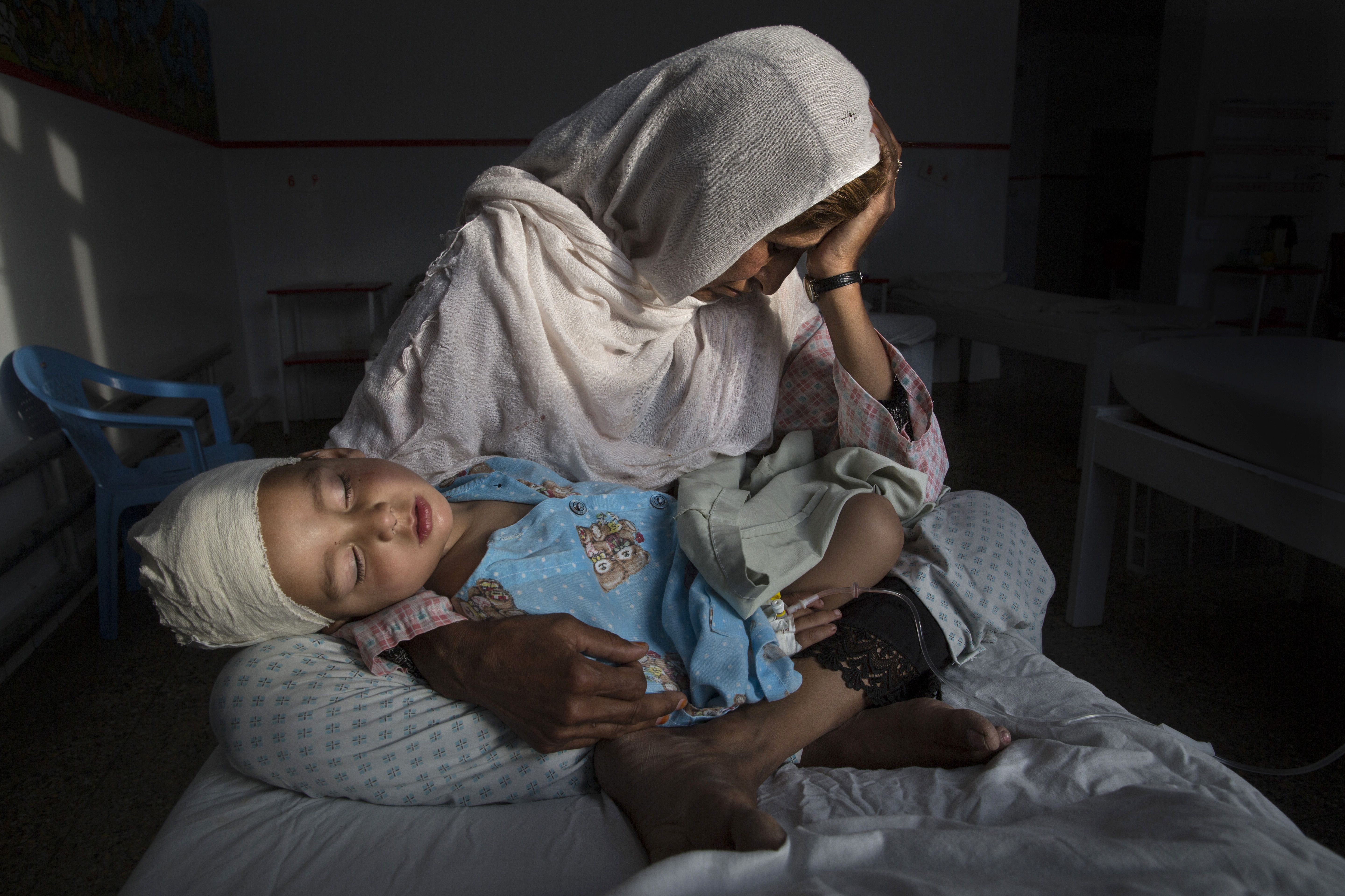 Najiba holds her nephew, Shabir, who was injured from the same bomb blast that killed his sister. Najiba watched over the children while Shabir’s mother buried her daughter. Image by Paula Bronstein. Afghanistan, 2015. 