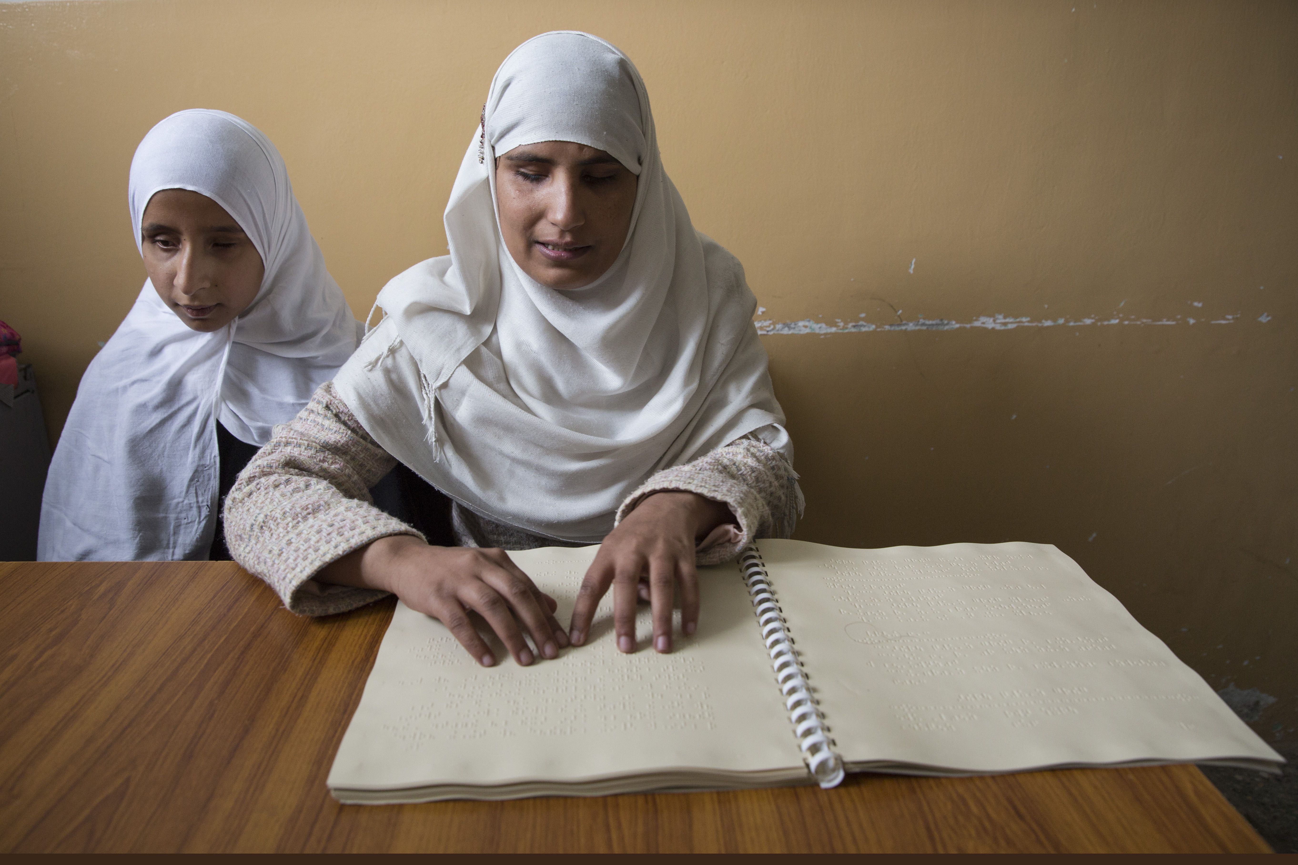 At the Kabul School for the Blind, Ruma reads from a braille book. She lost her sight in a rocket attack. Image by Paula Bronstein. Afghanistan, 2015. 