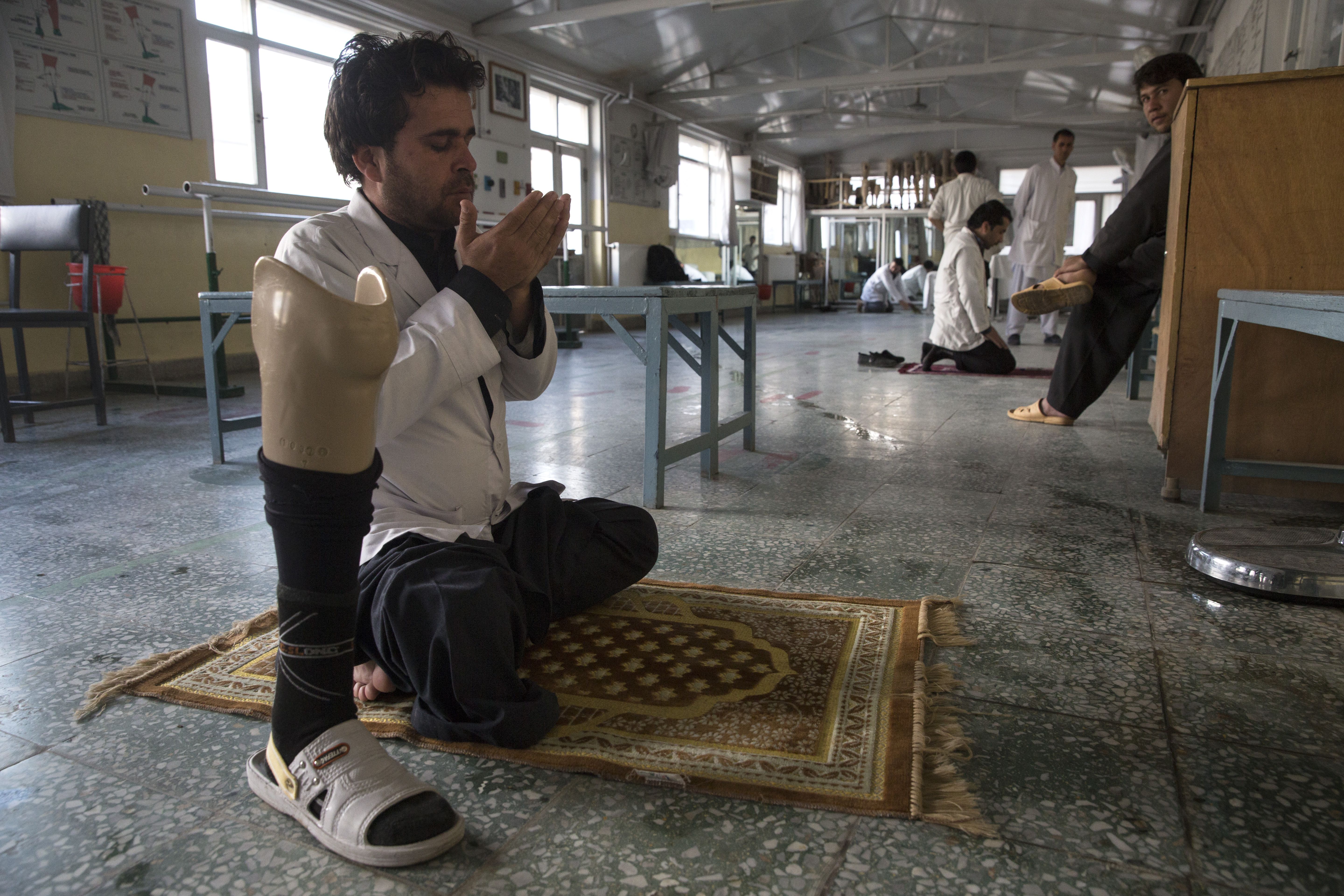 At the orthopedic center, a handicapped employee prays after finishing his duties. Image by Paula Bronstein. Afghanistan, 2015. 