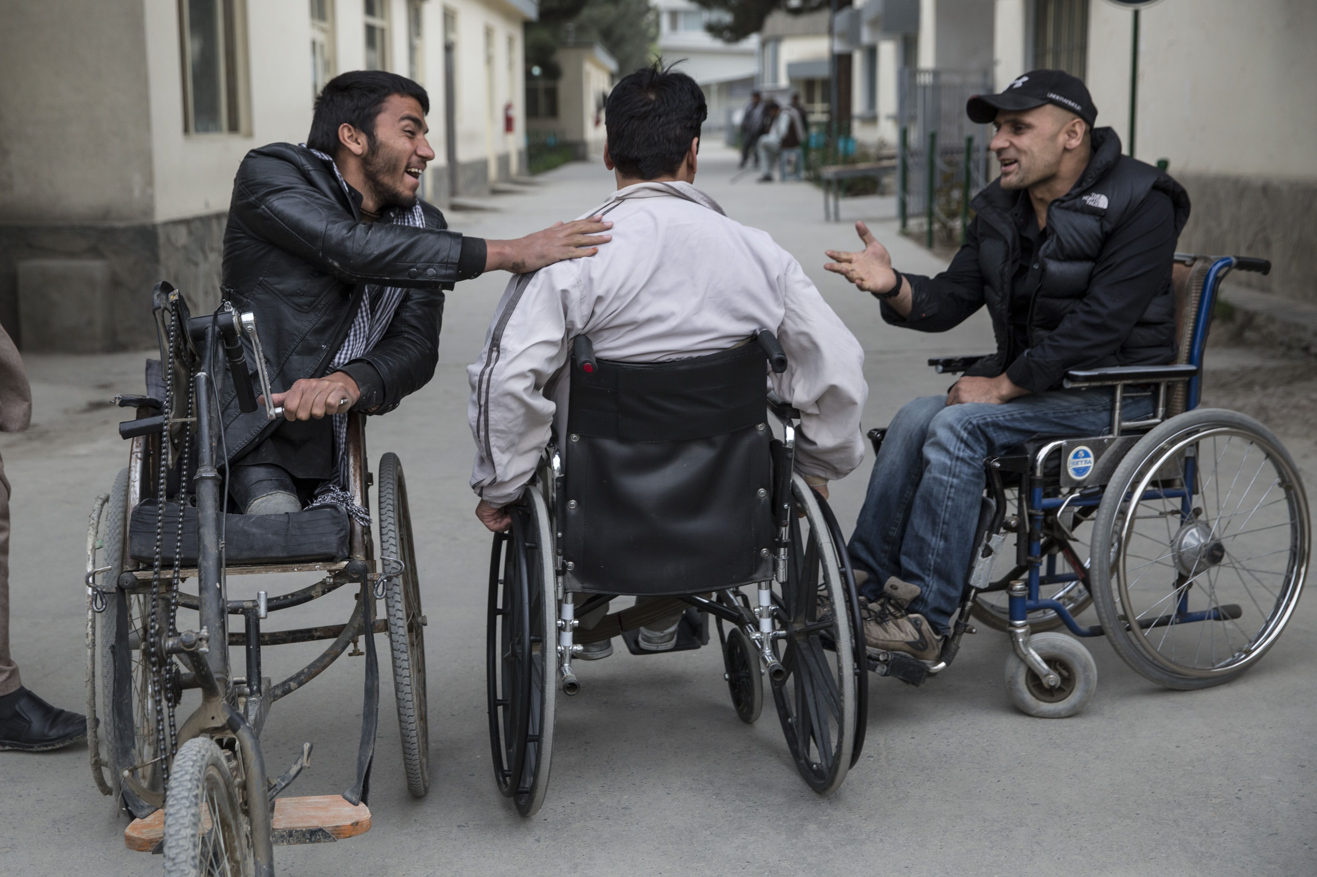 Nasrullah, left, chats with friends outside the orthopedic center. Image by Paula Bronstein. Afghanistan, 2015.