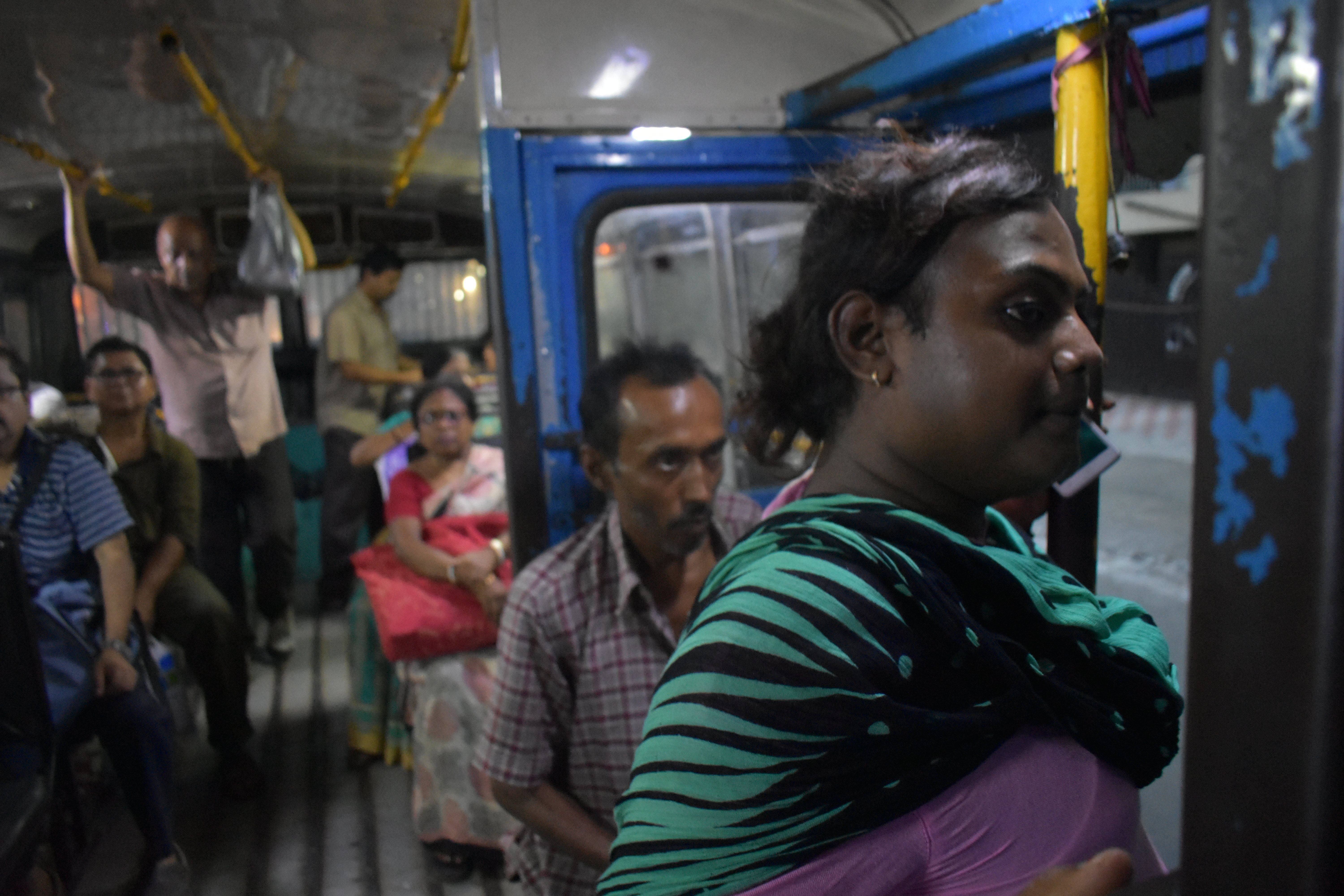 Sintu, like many transgender individuals, relies on street economies such as dancing for survival. Traveling all across Kolkata, she spends a large portion of her life on public transportation. Buses and trains across India are divided by gender with painted signs. There is only standing room on this bus, but she always sits in the "Gentlemen's" section. Image by Siyona Ravi. India, 2017.