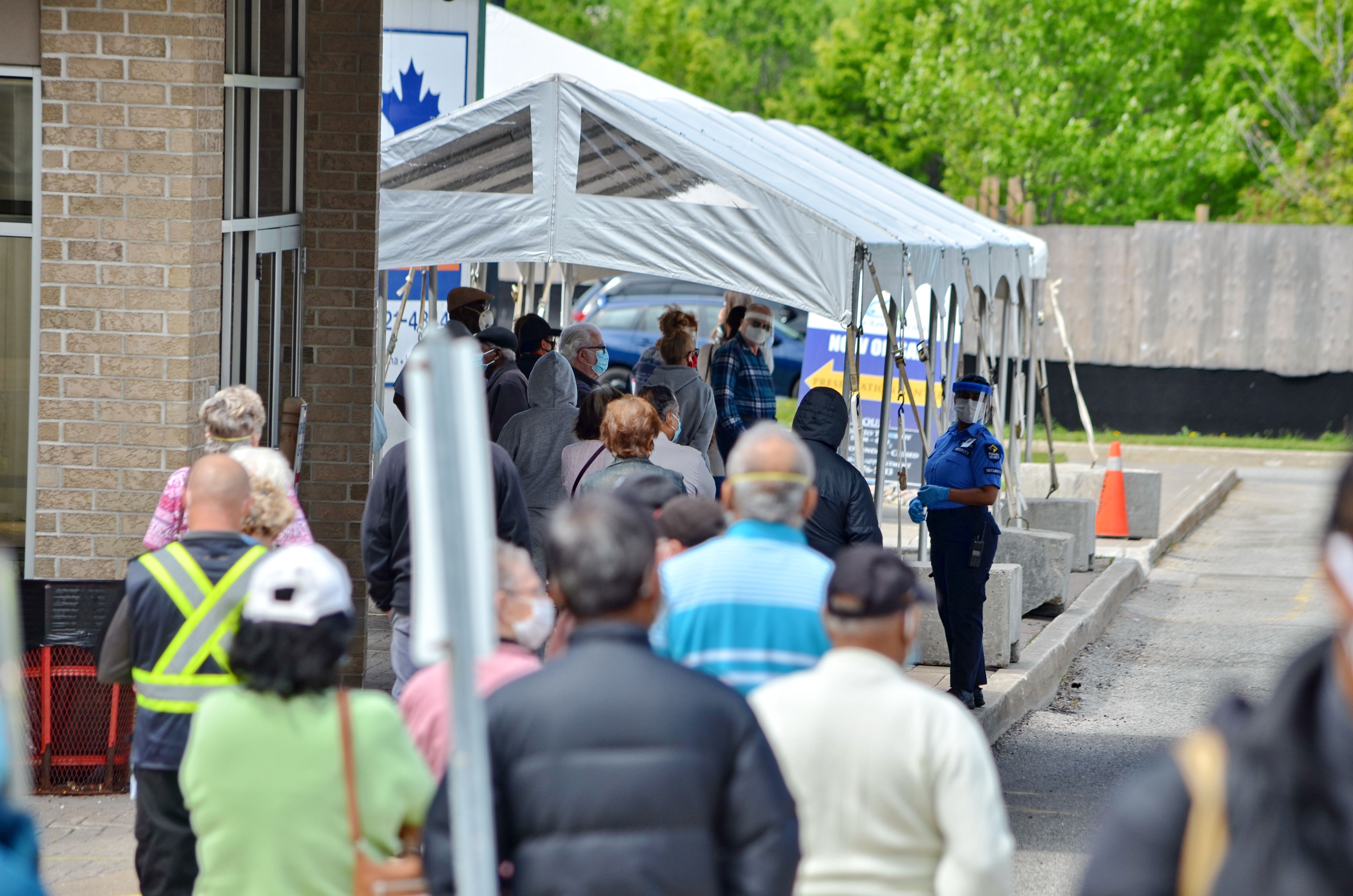People wait in line for a COVID-19 test at a pop-up mobile Assessment Centre. Image by Bob Hilscher/Shutterstock. Canada, 2020.