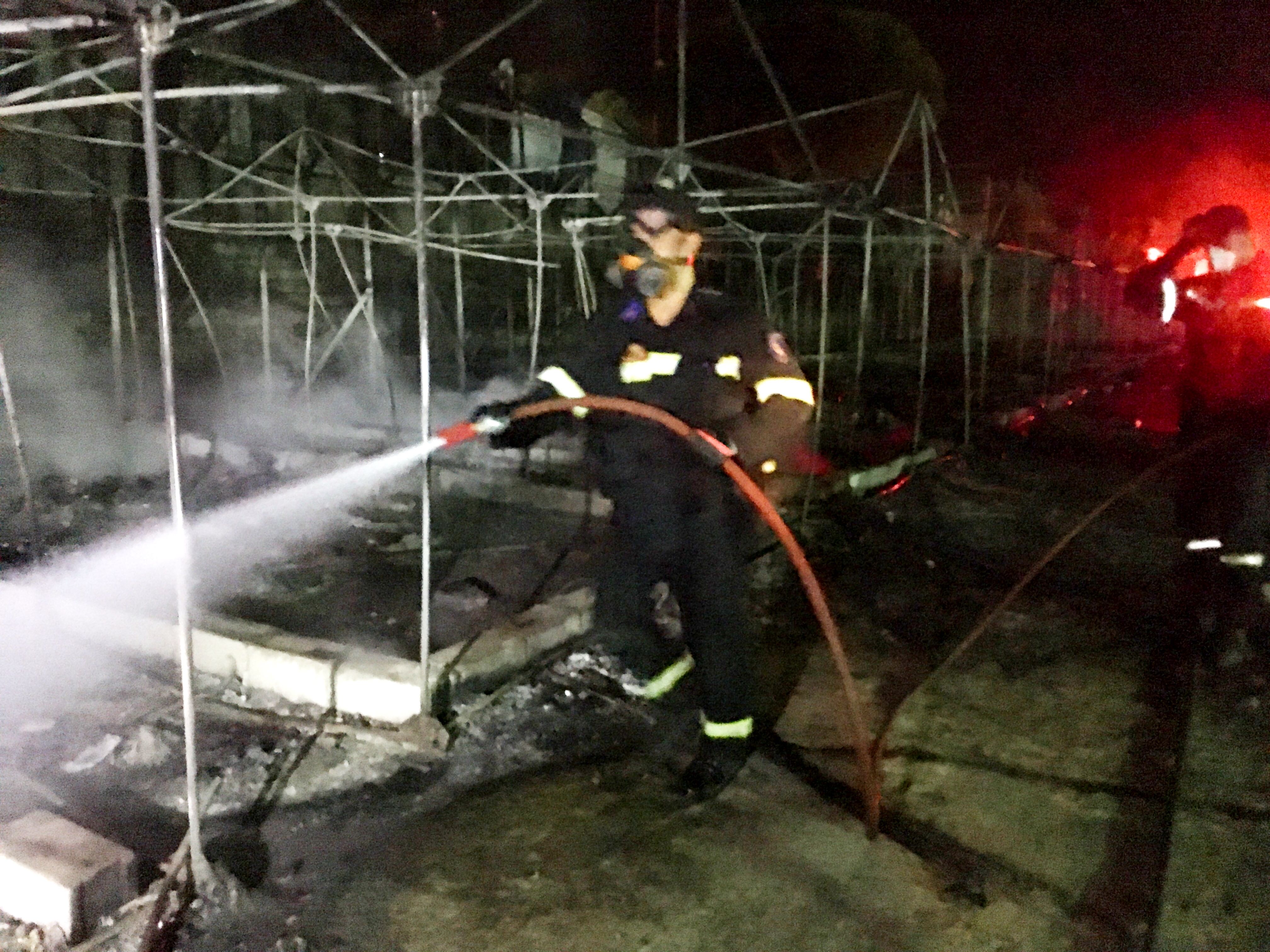 A fireman douses the flames among burned tents at Moria camp after a fire that ripped through tents and destroyed containers during violence among residents. Image by Jeanne Carstensen. Lesbos, Greece, 2016.