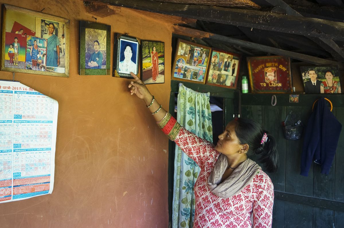 Krishna Kumari B.K. shows off family photos hanging in her rural Nepal home. Image by Yam Kumari Kandel. Nepal, 2016. 
