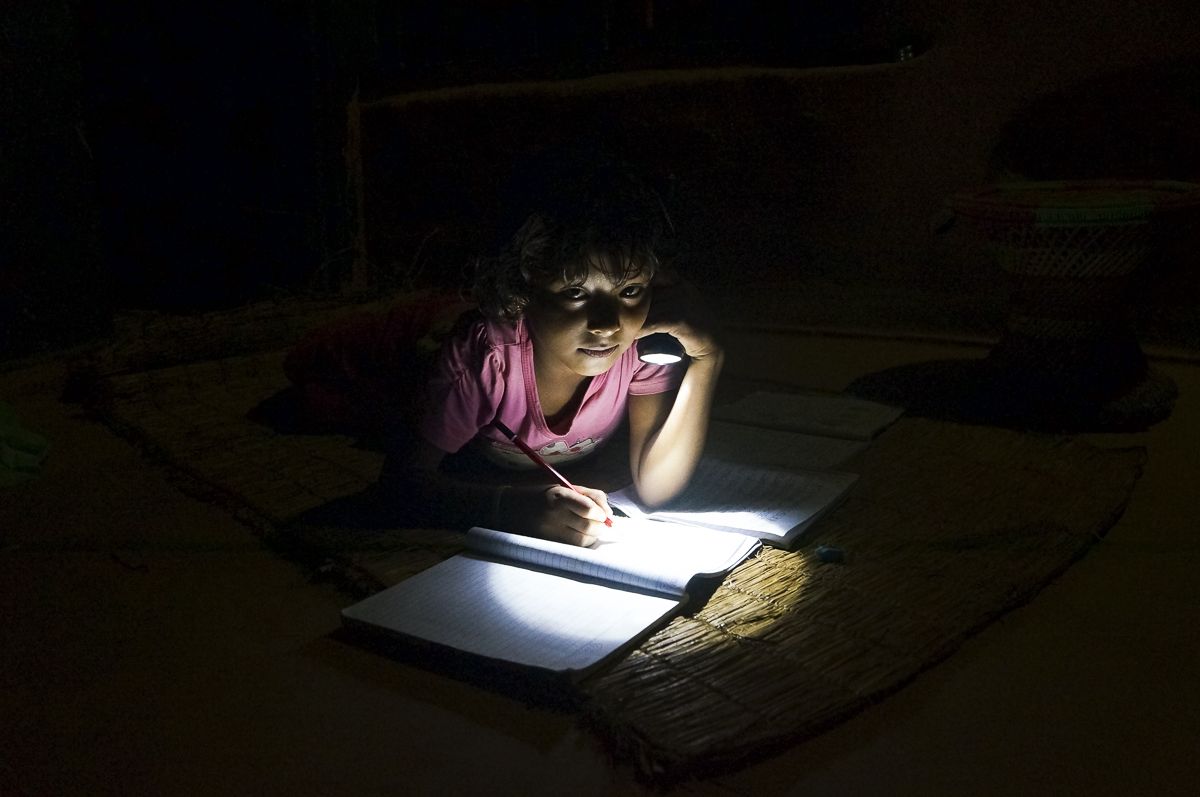 Lozan B.K. uses a flashlight to study at home. The family does not have electricity. 
