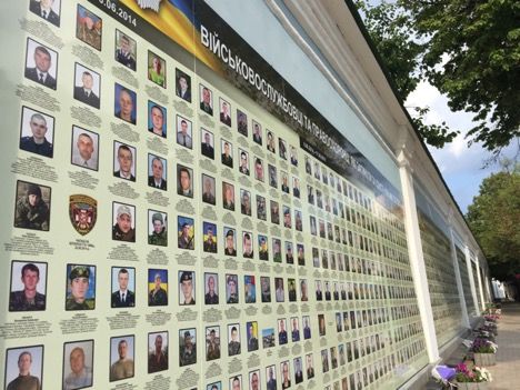A wall of remembrance stands along the outside of the famous St. Michael’s Cathedral in Kyiv. This wall contains photos of all fallen soldiers killed from 2014 to 2017 in the conflict. Because women were not official combatants, women are almost completely absent from this place memorializing soldiers' contributions to the war. Image by Taylor Damann. Ukraine, 2019.