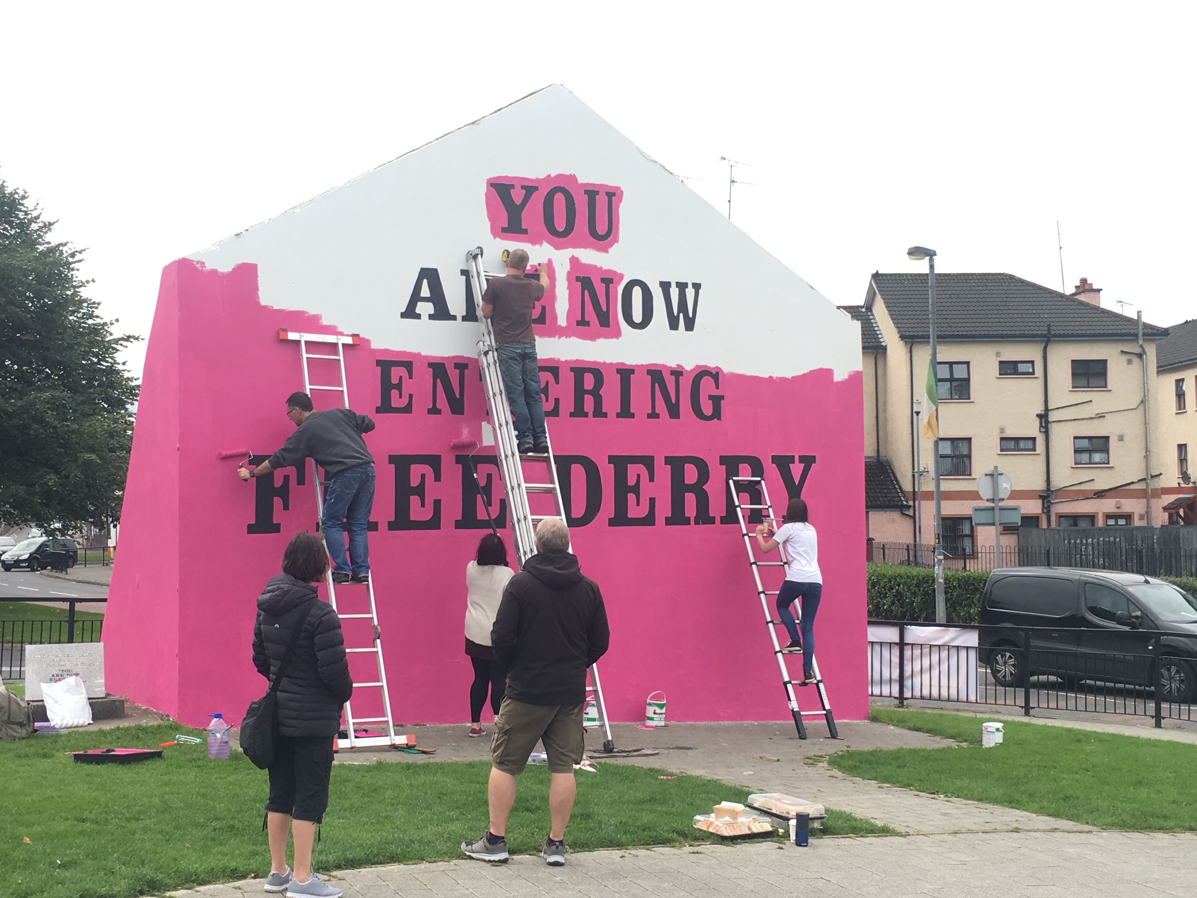 “You Are Now Entering Free Derry” Mural. The Free Derry mural, signifying police ‘no go’ zones during The Troubles, is painted pink for Pride. Photo by Julia Canney. Northern Ireland, 2018.