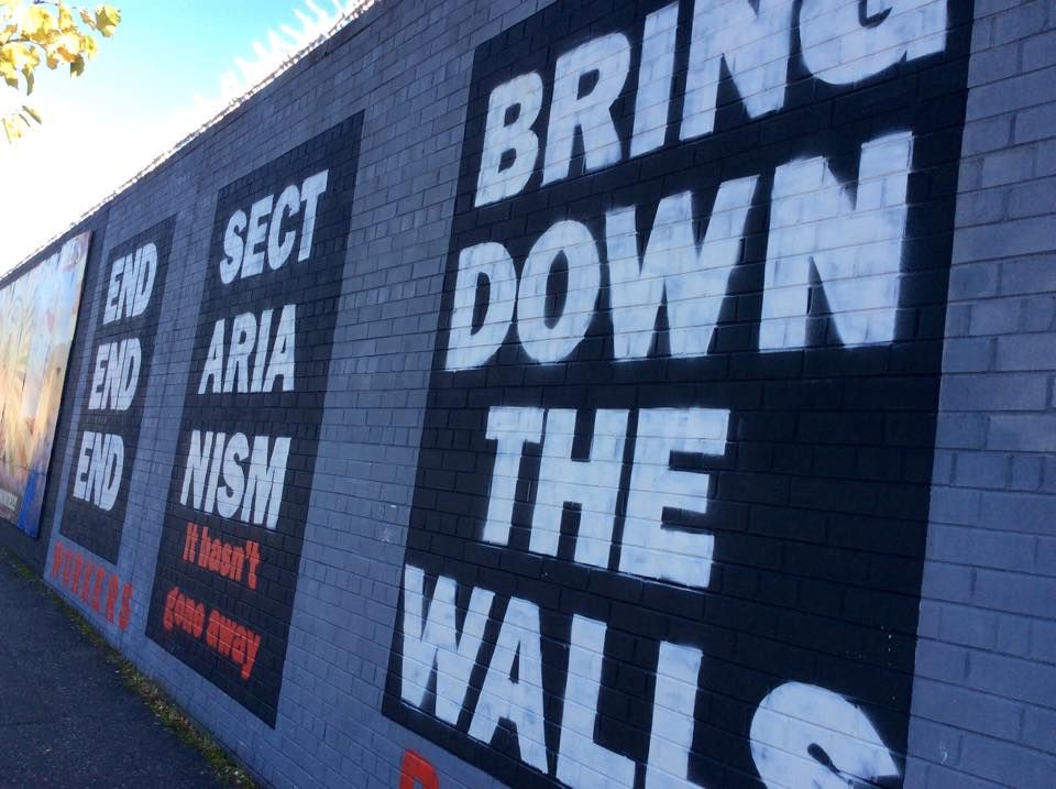 A mural reading 'End Sectarianism: Bring Down The Walls' on the Falls Road mural wall in Belfast. Image by Julia Canney. Northern Ireland, 2018.