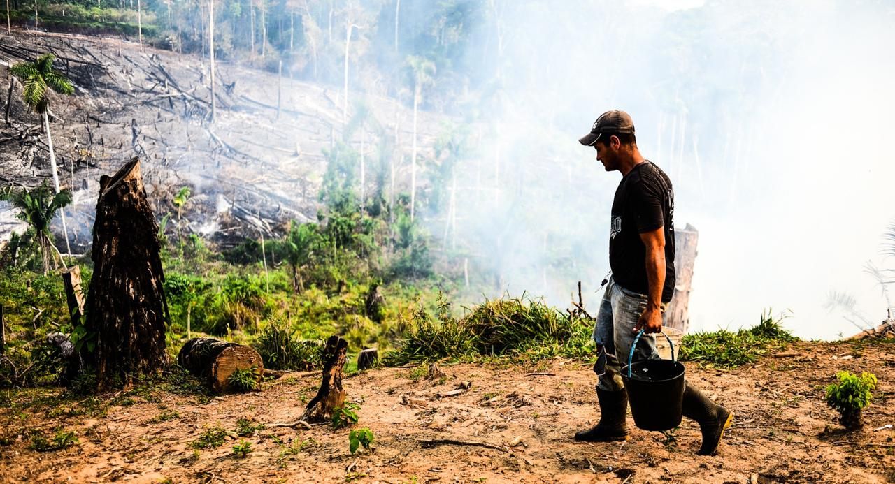 Farmer carries bucket of water in an attempt to fight the burning flames inside his property after being caught by Imac, National Force and Army staff. Image by Jardy Lopes/Notícias da Hora. Peru, 2019.
