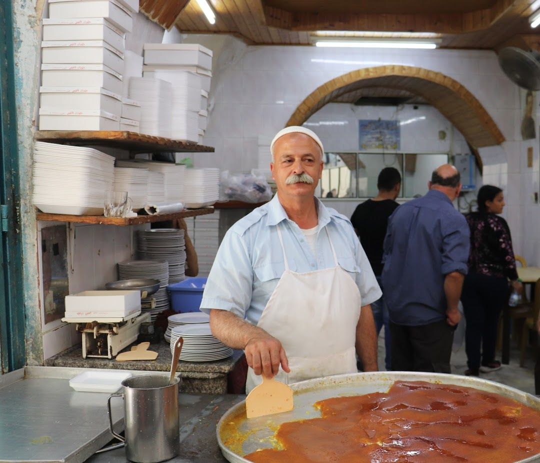 The owner of Al-Aqsa Knafeh, a 60-year-old institution, doles out 40 trays of this cheesy, sweet confection every day, all day. Many restaurants use food coloring and other artificial additives, but Al-Aqsa keeps the ingredients simple and natural. Image by Carly Graf. Palestine, 2019.