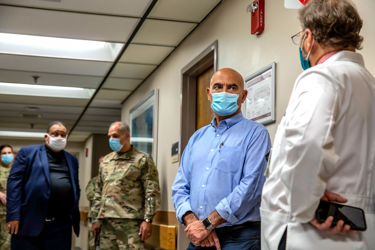 Operation Warp Speed leaders Moncef Slaoui (second from right) and Gen. Gustave Perna (second from left) speak with Cincinnati physicians Carl Fichtenbaum (far right) and O’dell Moreno Owens (far left) during a visit to one of the sites for the efficacy trial of Moderna’s COVID-19 vaccine candidate. Image courtesy of University of Cincinnati Health. United States, 2020.