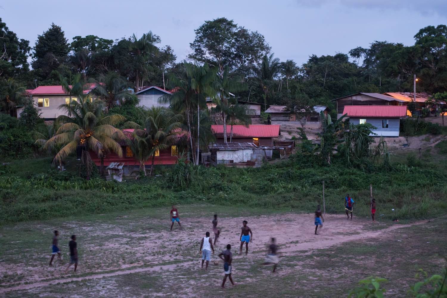 People play soccer as dusk falls on the village of Adjuma Kondre in Suriname. The village's water sources have been impacted by Alcoa's nearby mining operations. Image by Stephanie Strasburg. Suriname, 2017.