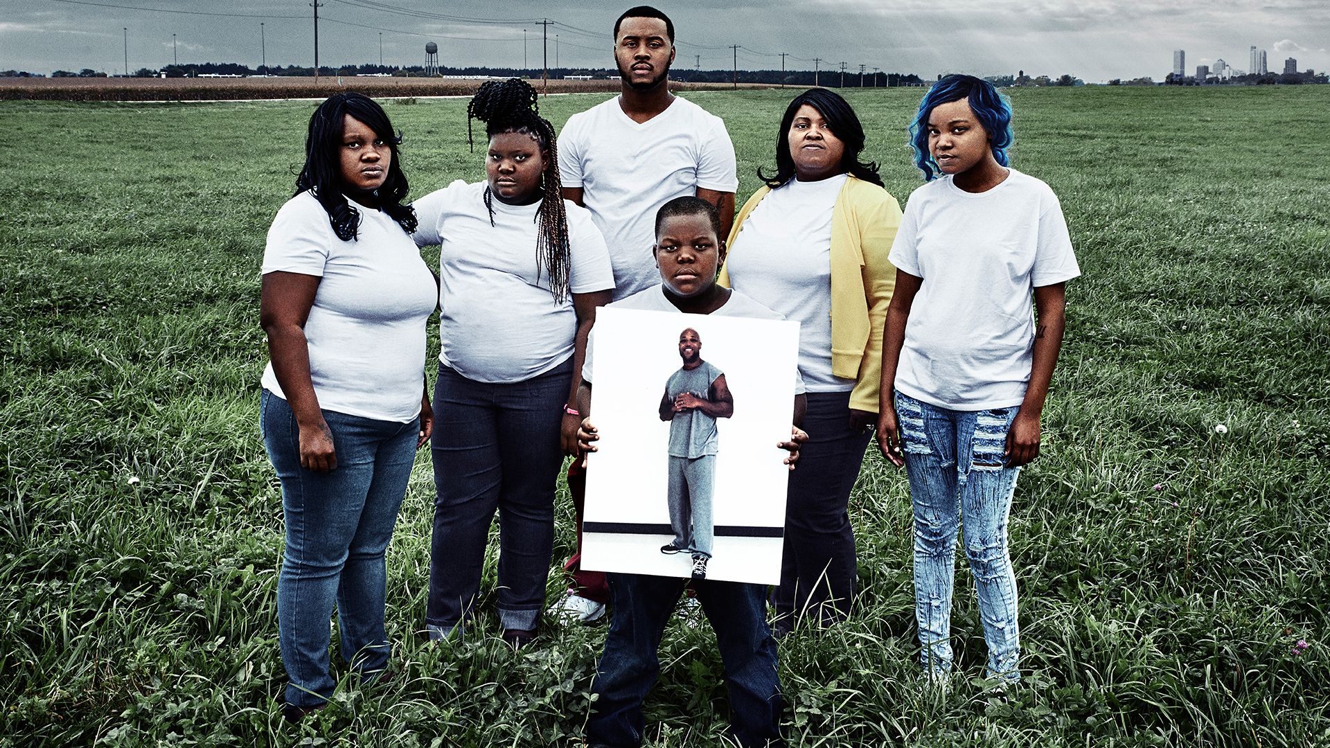 The Walker family poses with a photo of their incarcerated father and husband, Baron, in a still from Milwaukee 53206. Image courtesy of Transform Films. United States, 2016.