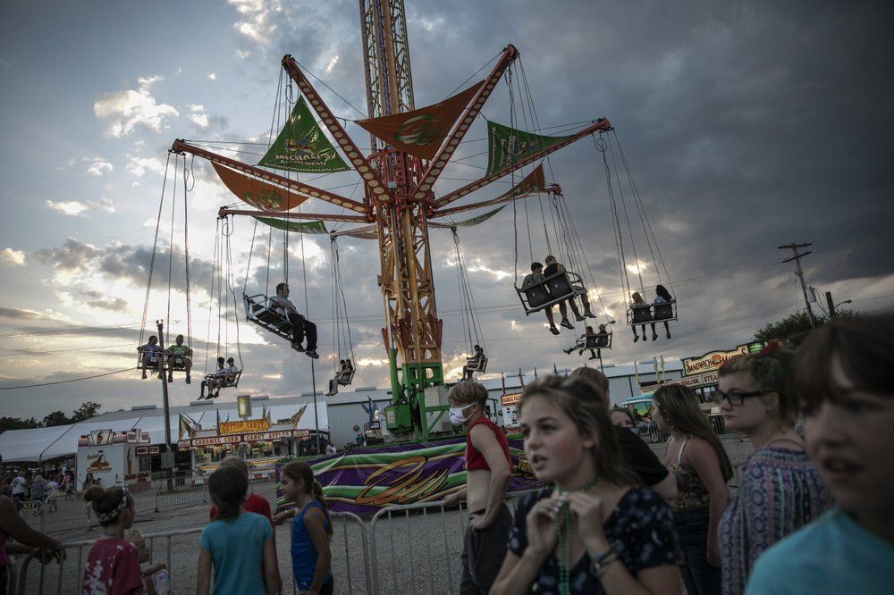 People wait to ride a revolving swing at the Perry State Fair in New Lexington, Ohio, Friday, July 24, 2020. In the towns that speckle the Appalachian foothills of southeast Ohio, the pandemic has barely been felt. Coronavirus deaths and racial protests - events that have defined 2020 nationwide - are mostly just images on TV from a distant America. Image by Maye-E Wong/AP Photo. United States, 2020.