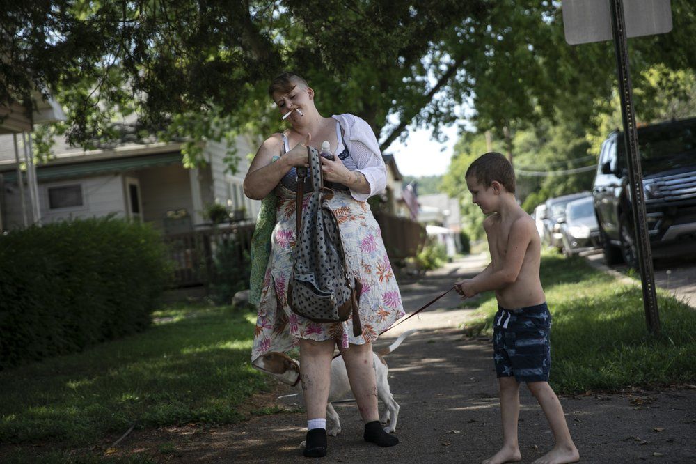 Brittany Cunningham 31, walks down the street with her nephew and his dog in Nelsonville, Ohio, on Friday, July 24, 2020. Brittany, a heroin addict, has been homeless for ten years. Her stories range from across a life steeped in addiction and badly chosen boyfriends to a deep love for music. Image by Maye-E Wong/AP Photo. United States, 2020.